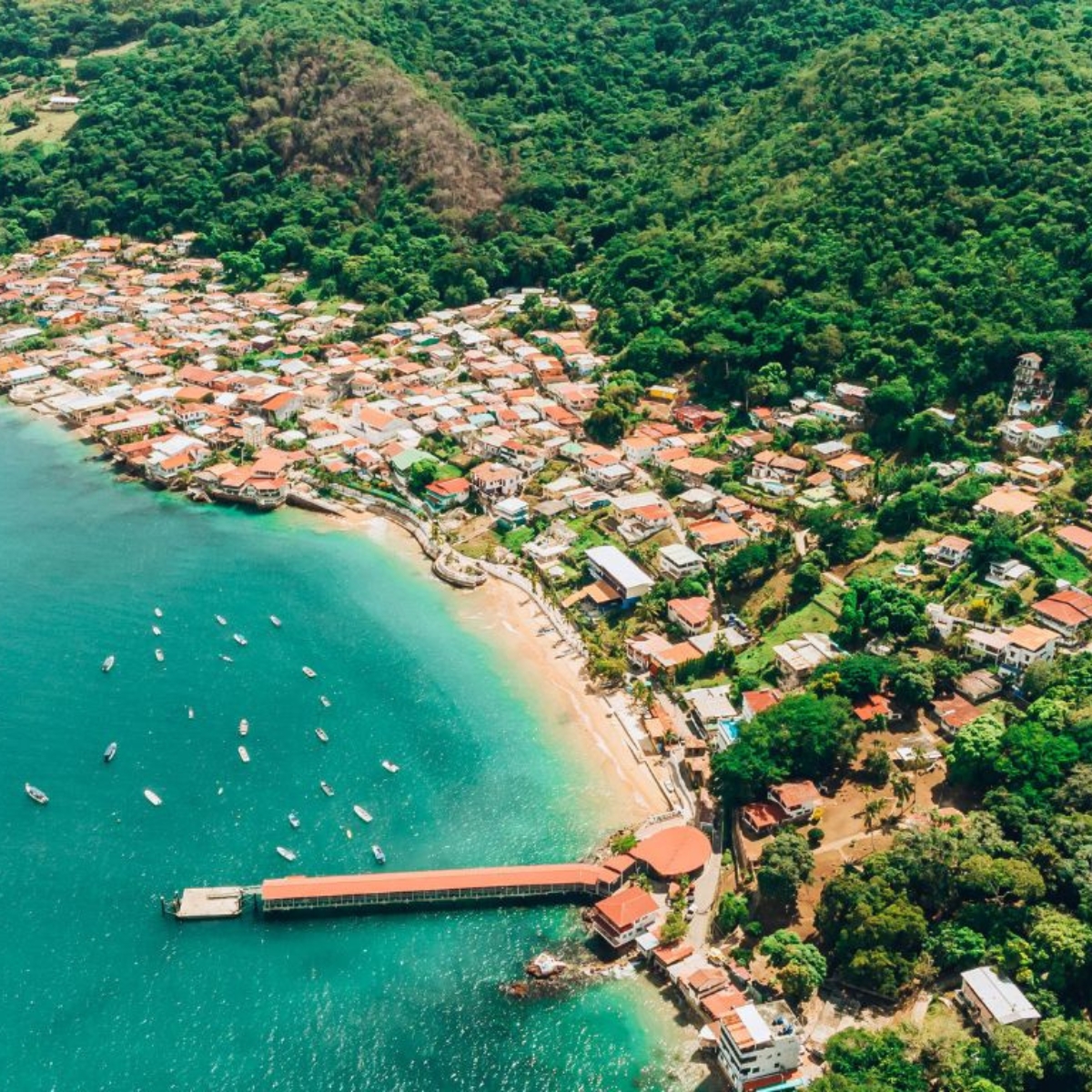 Bahía de República Dominicana. Agua turquesa. Mar y barcos navegando. Montañas con árboles.